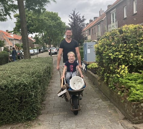 Vader met dochter in de kruiwagen